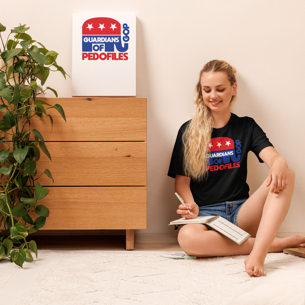 Person wearing a shirt with a logo and text, sitting on the floor with a book.